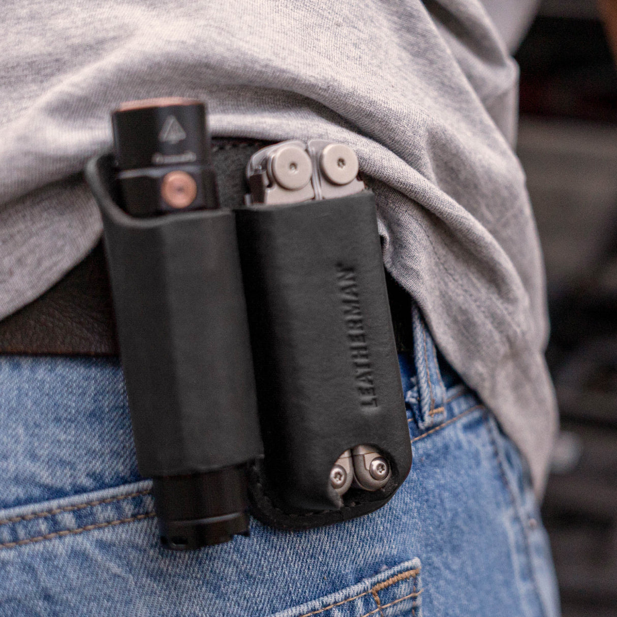 Translation missing: fr.Black leather belt sheath holding a multitool and flashlight on a person’s hip