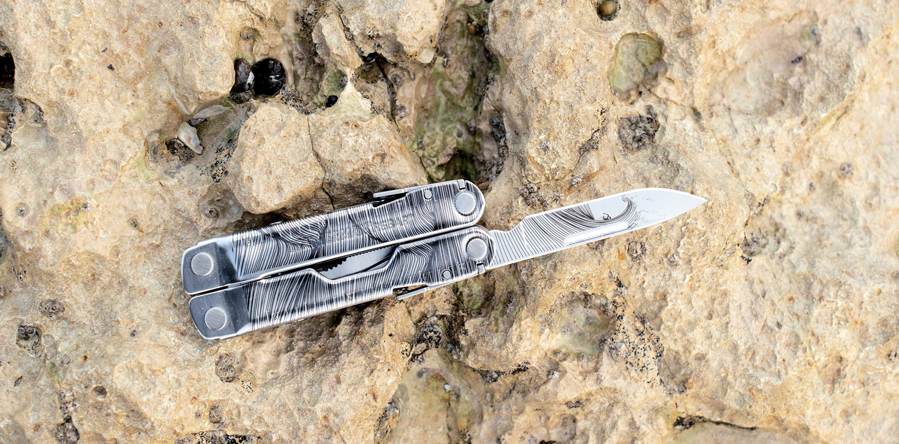 Leatherman Rebar® multi‑tool partially open on a rock surface, showing the knife blade.
