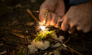 Translation missing: en.A person using the ferro rod on a Leatherman Signal® to create sparks while preparing kindling in the forest