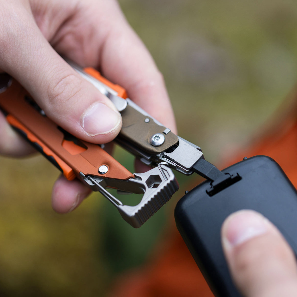 Translation missing: es.A person using the flat bit on a Tundrascape Leatherman Signal® to open a battery compartment