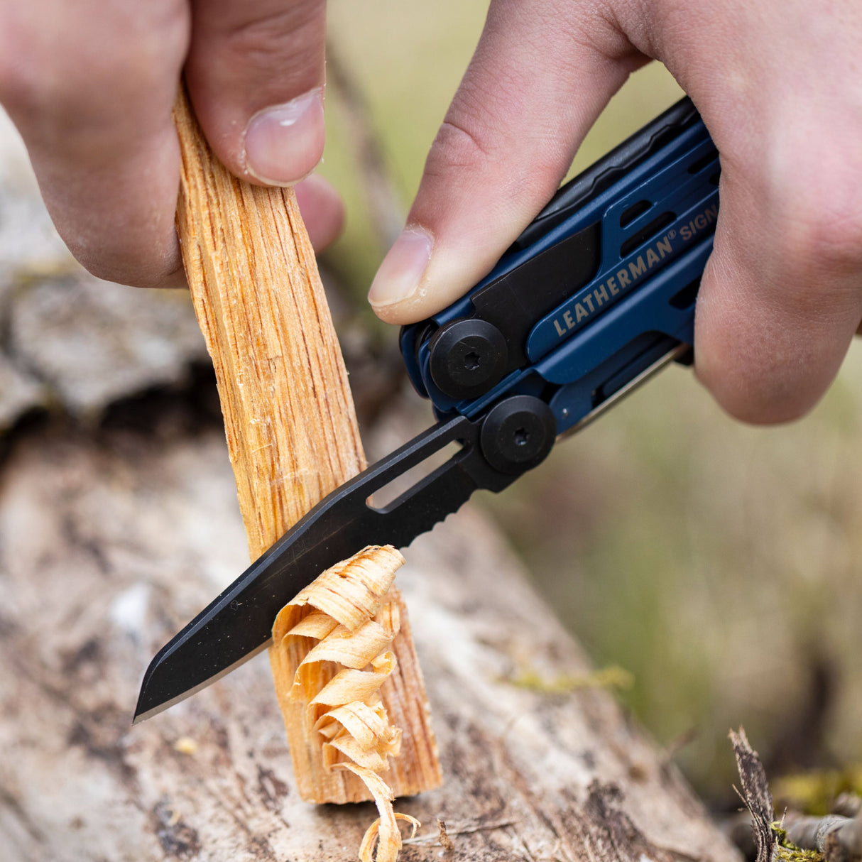 Translation missing: de.A person using the combo knife on a Nocturnal Leatherman Signal® to shave a piece of wood