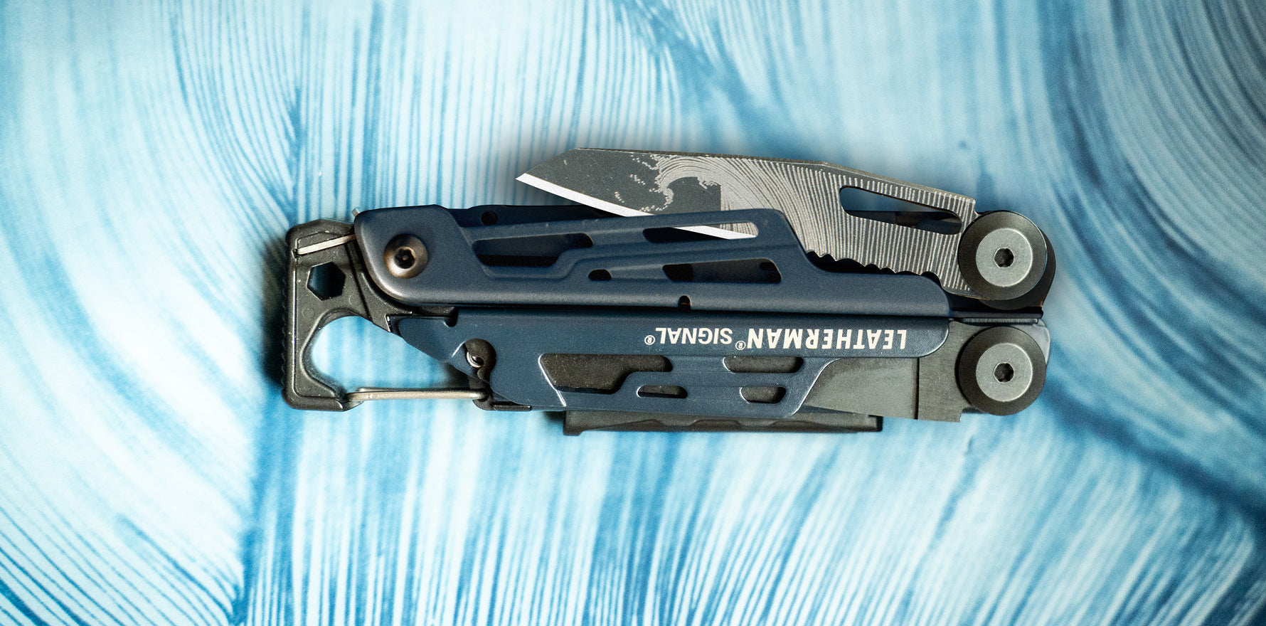 Leatherman Signal® World Artist Day 2026 multi‑tool shown closed on a blue background, highlighting the engraved blade and compact design.