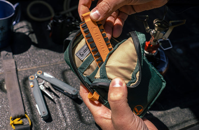 Translation missing: de.Person holding Hunter Leatherman® Tool Pouch with an orange Bit Kit, showcasing tools and outdoor setting