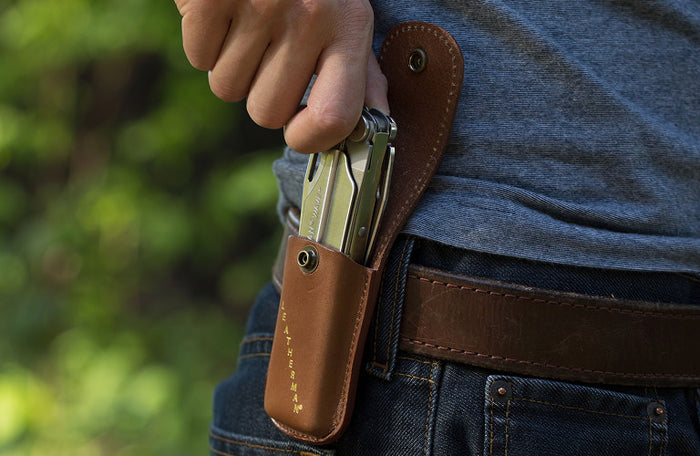 Translation missing: de.A person reaching for a Stainless Steel Leatherman Wave® Plus multi-tool in a brown leather sheath on their hip