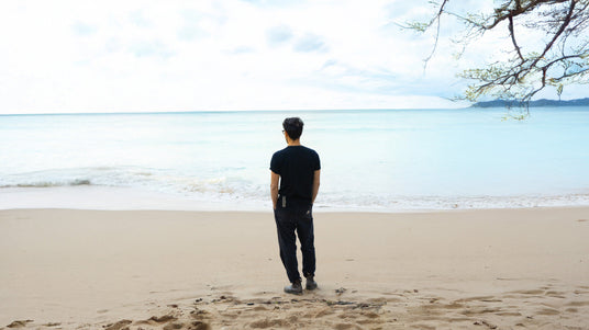 Translation missing: en.The Minimalist Wave artist standing on a sandy beach, gazing out at the peaceful ocean