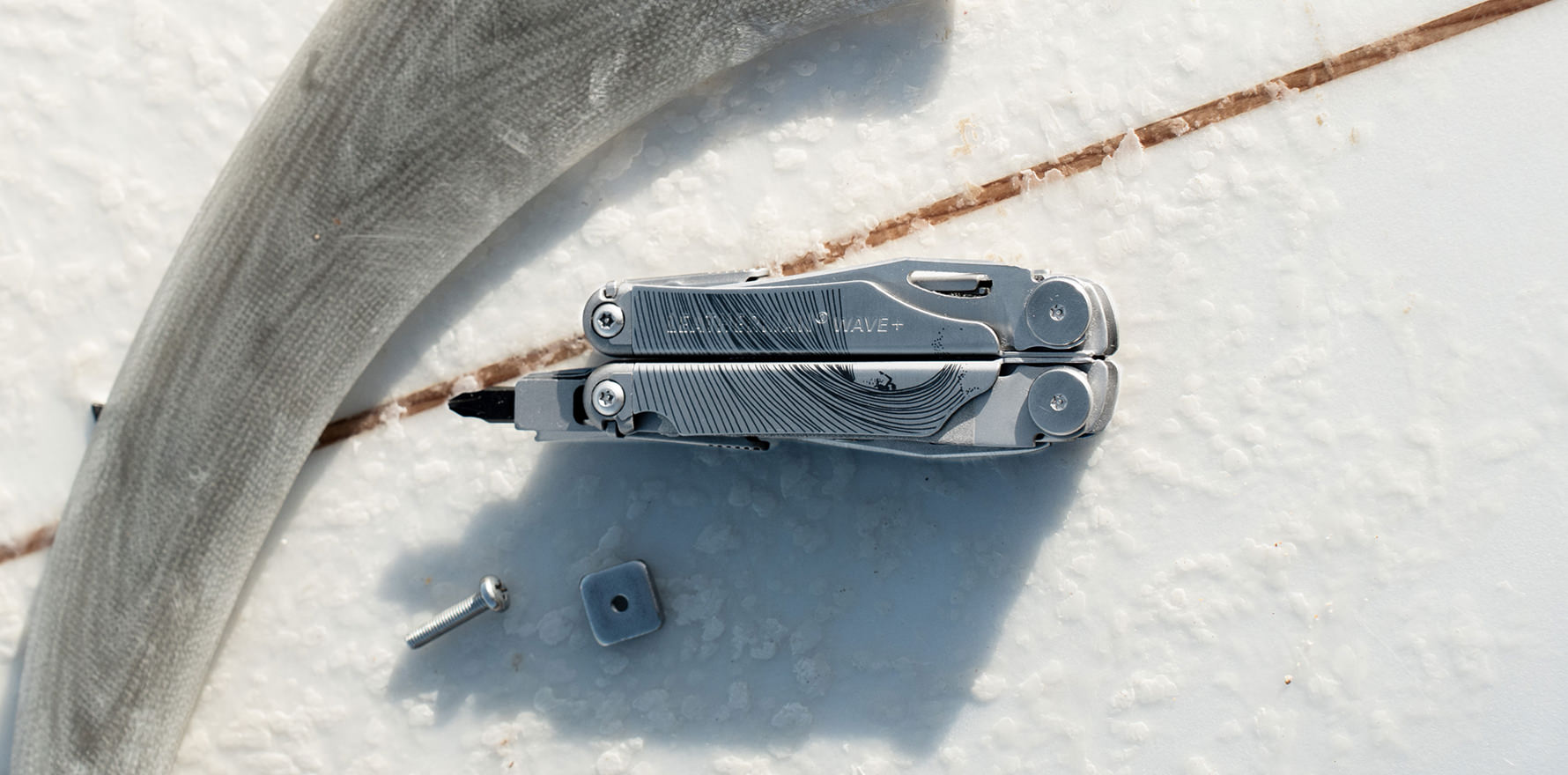 Stainless steel customized Leatherman Wave with a minimalist lined design on top of a surfboard
